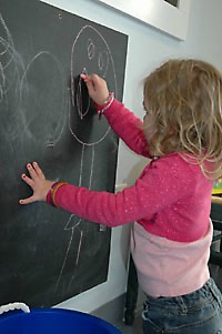 Child practicing hand/eye coordination at a chalkboard.