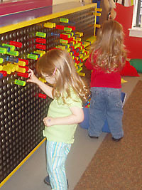 Children engaging in hand/eye coordination exercise at pegboard.